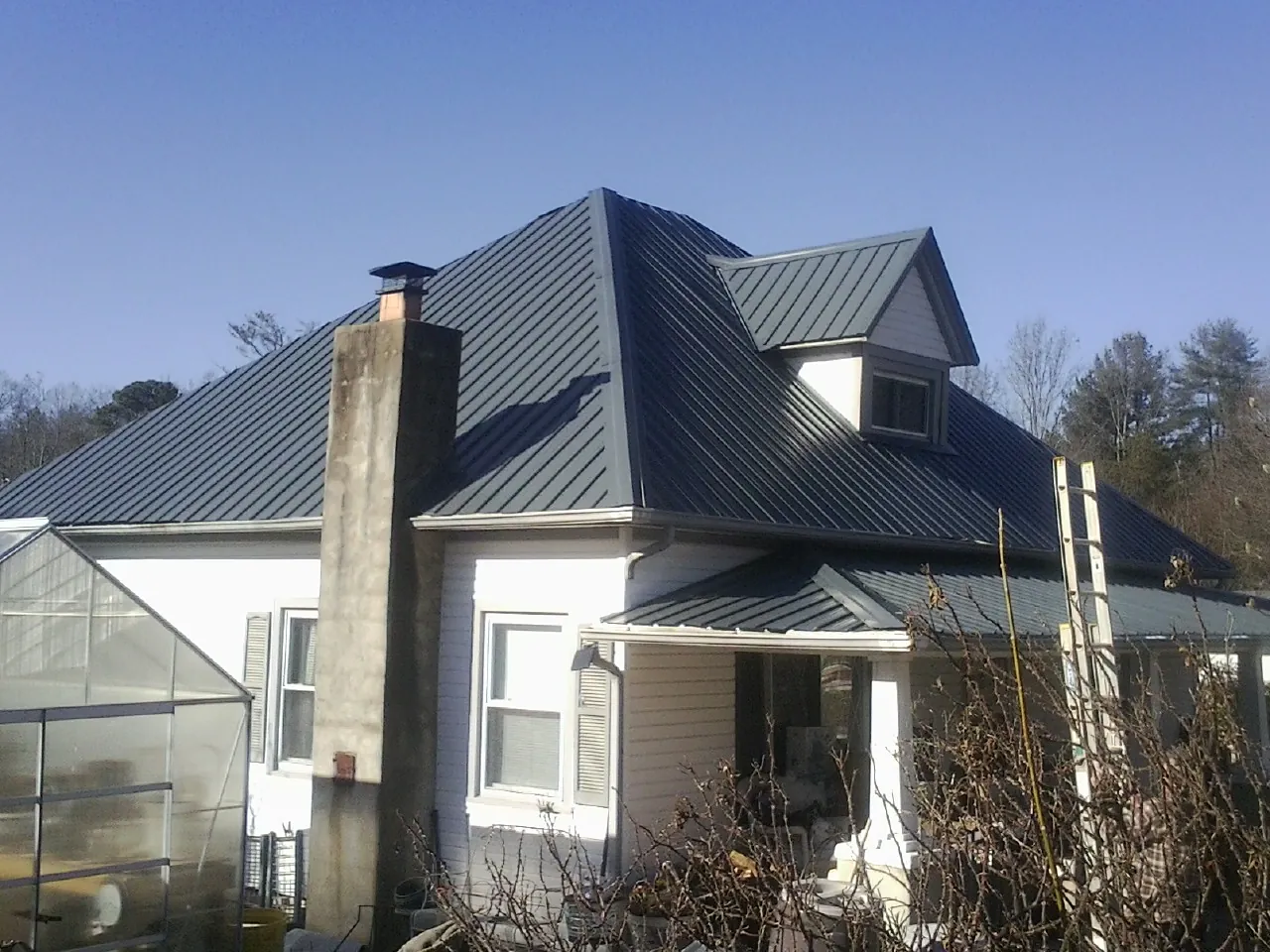 Dark blue standing seam metal roof on a white farmhouse with dormer — Slate & Tile Roof Repair by Roofing Brothers in Fort Edward