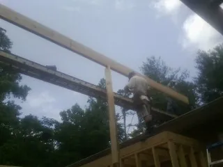 Carpenter setting a ridge beam over a new addition frame — Ice Dam Removal by Roofing Brothers in Fort Edward