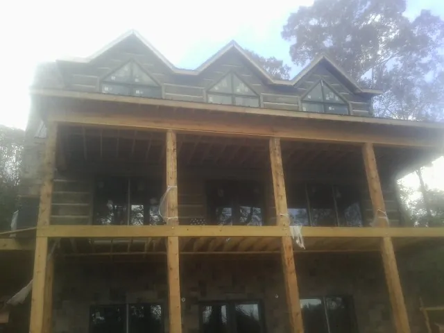 Dormers and porch framing on a large log home under construction — Roof Coating work by our crew in Fort Edward