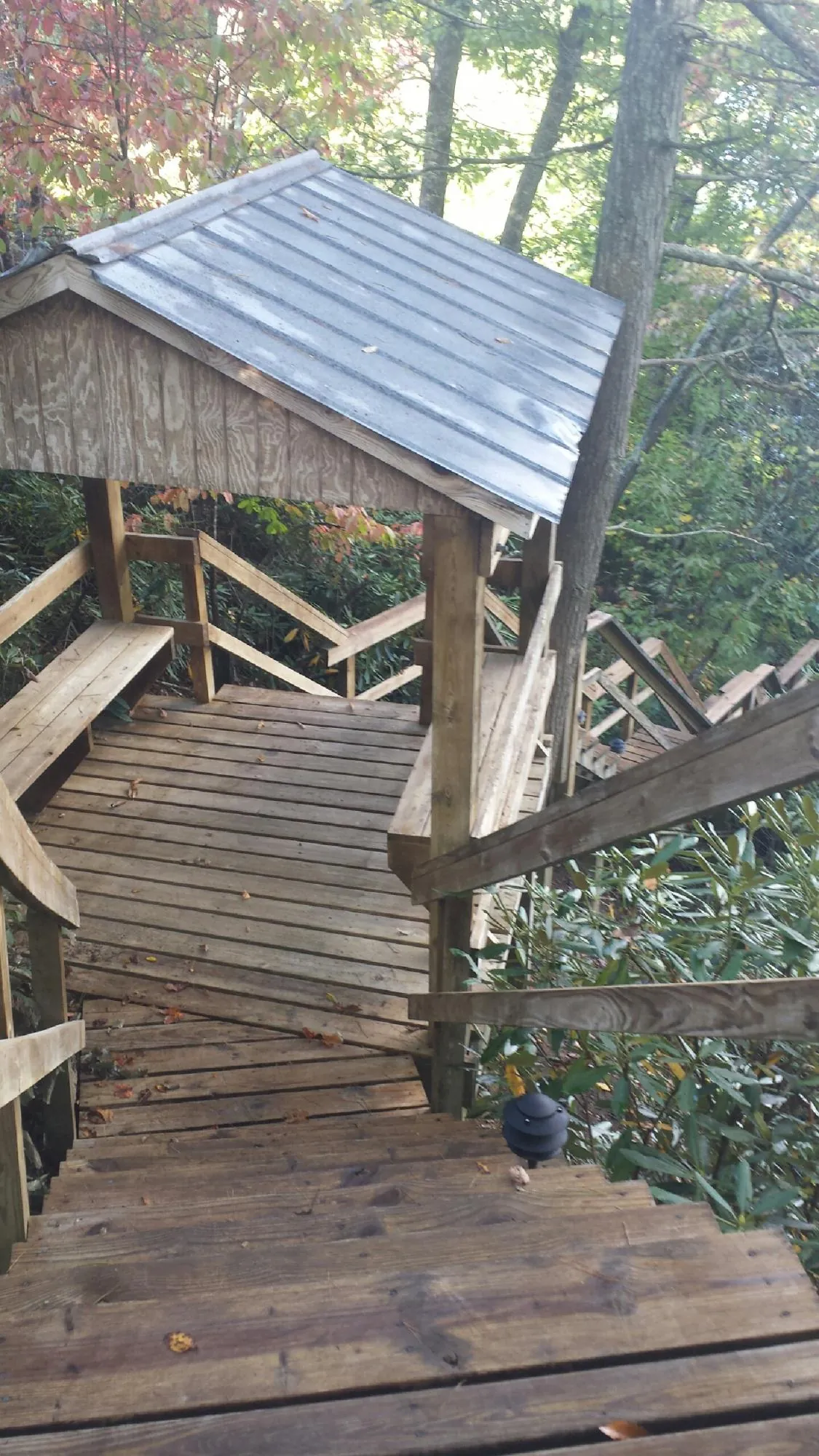 Metal roofed shelter over wooden steps on a wooded walkway — Skylight Repair & Installation work by our crew in Fort Edward