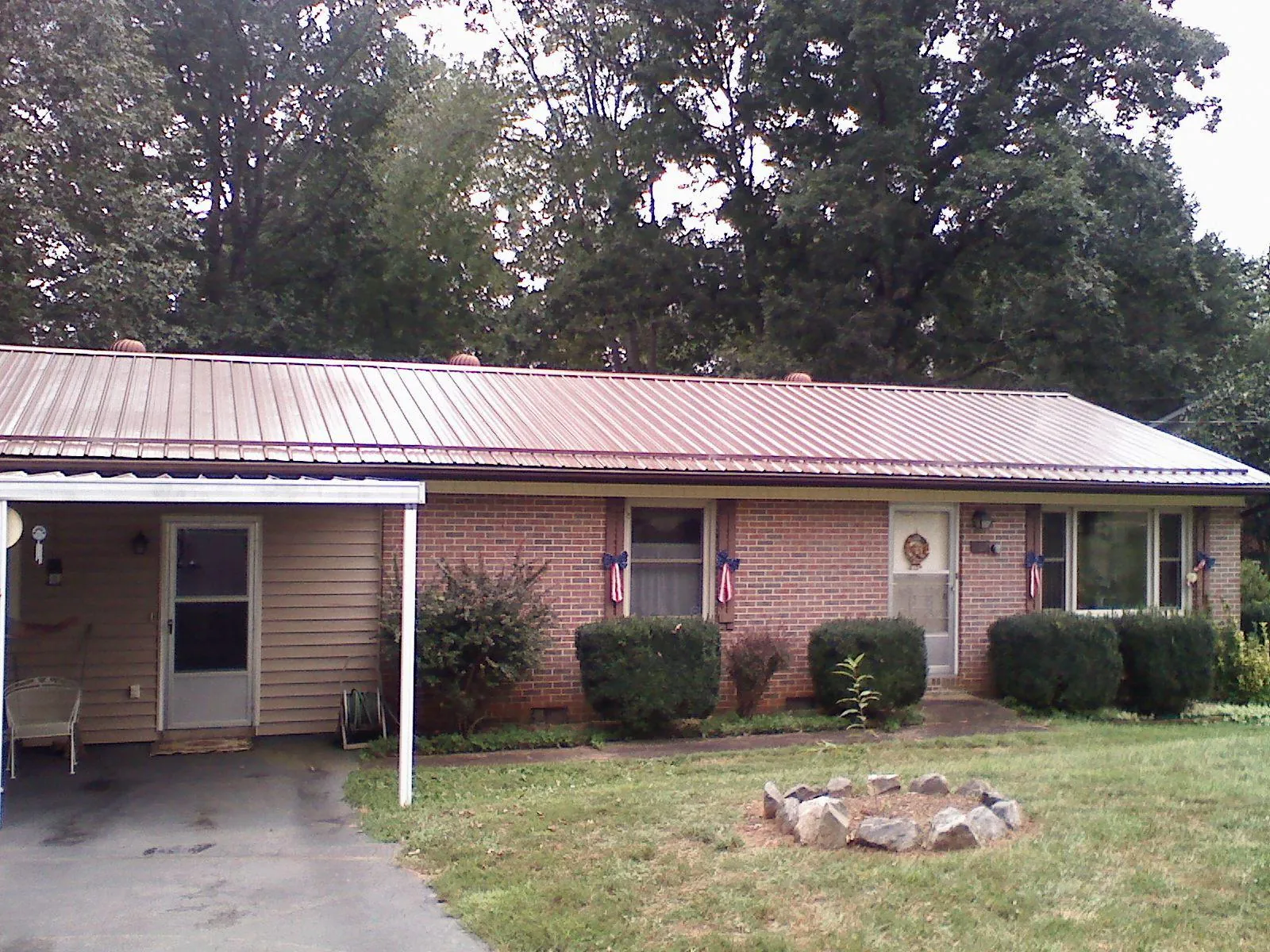 Bronze metal roof and carport on a brick ranch home — Roof Repair work by our crew in Fort Edward
