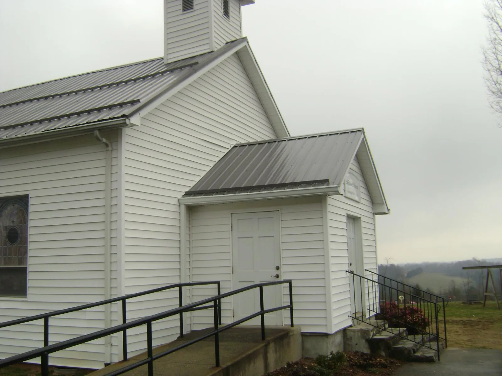 Gray metal roof on a white clapboard church with a steeple in Fort Edward