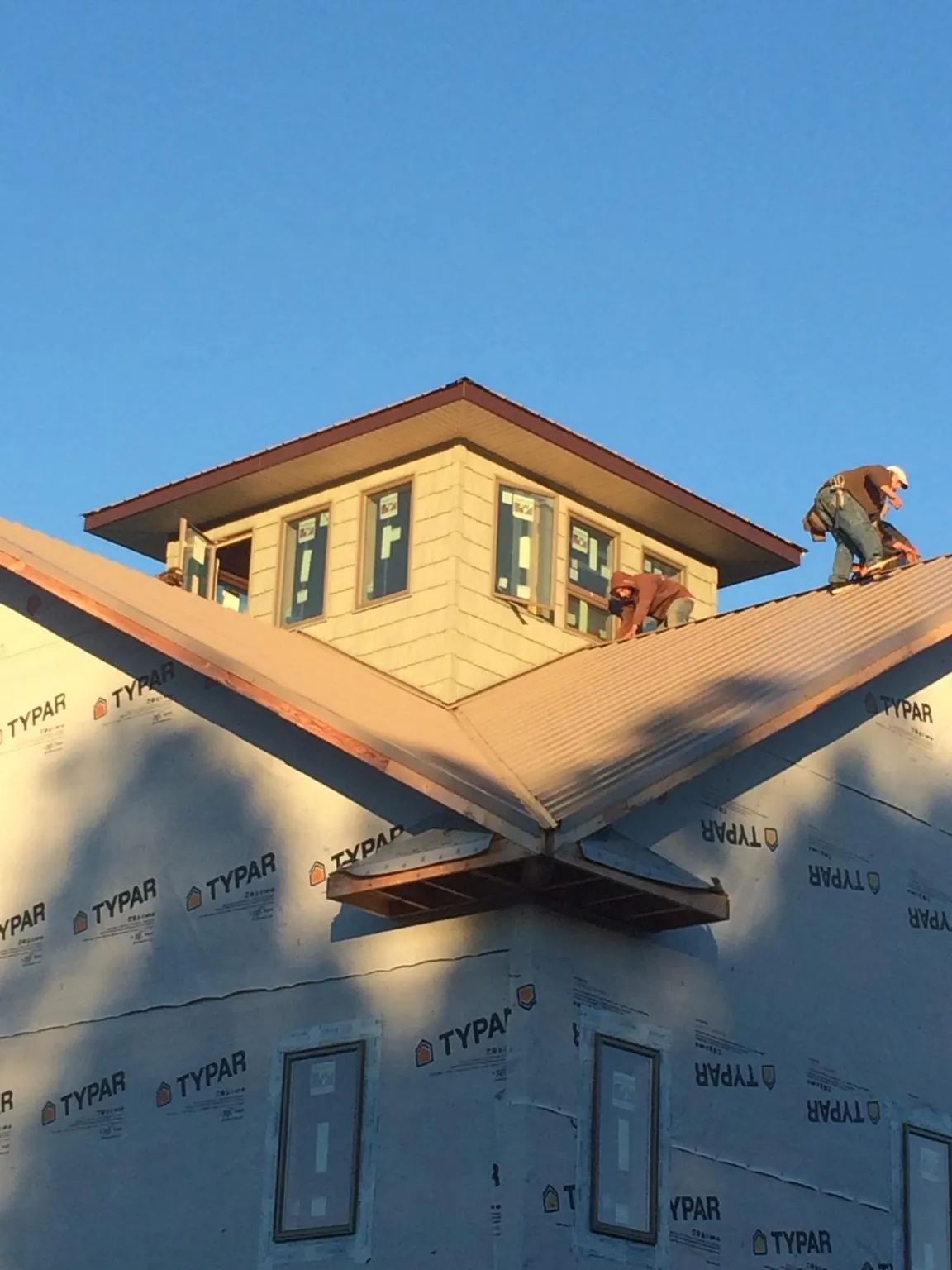 Roofers working around a rooftop cupola on a new metal roof at sunset — Roof Waterproofing in Fort Edward by Roofing Brothers